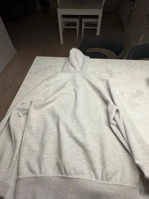  Polo Ralph Lauren Ljusgrå hoodie med dragkedja - Snygg ljusgrå hoodie från Polo Ralph Lauren med dragkedja framtill och två fickor. Klassisk huva med dragsko och diskret logga på bröstet. Tillverkad i mjukt sweatshirtmaterial som är perfekt för chill dagar.