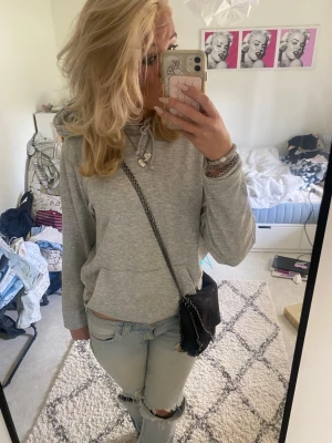 Ljusgrå hoodie - En stilren ljusgrå hoodie med huva och dragsnören. Hoodien har en klassisk känguruficka framtill och är gjord i mjukt sweatshirtmaterial. Perfekt för en chill och avslappnad look. Passar till jeans eller mjukisbyxor.