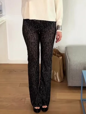 flared glitterbyxor - Säljer ett par svarta leggings med glittrande paljetter och ett snyggt mönster. De har hög midja och utsvängda ben, vilket ger en trendig siluett. Materialet är stretchigt och bekvämt, perfekt för dig som vill sticka ut lite extra. Byxbenen är upplagda. 