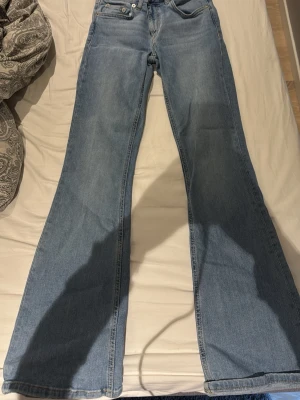 Ljusblå bootcut jeans - Säljer ett par ljusblå bootcut jeans med klassisk femficksmodell och normal midja. Jeansen har utsvängda ben och är tillverkade i mjukt denimtyg. Perfekta för en avslappnad och trendig look.
