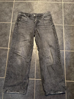 Baggy wide jeans i grå denim - Säljer ett par gråa baggy wide jeans. Jeansen har klassisk femficksdesign, raka ben och är tillverkade i denim. Perfekta för en avslappnad och trendig look.
