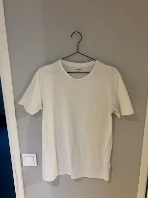 Vit t-shirt från Lindbergh - En klassisk vit t-shirt från Lindbergh i storlek M. T-shirten har rund halsringning och korta ärmar, tillverkad i mjuk bomull för en skön känsla. Perfekt basplagg att matcha med allt i garderoben.
