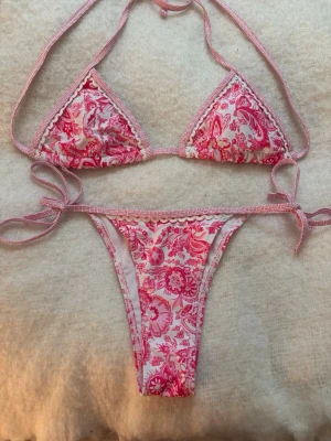 Rosa blommig bikini  - Supersöt bikini i rosa och vitt med blommigt mönster. Bikinin är helt oanvänd!! Säljer för att den blivit för liten för mej