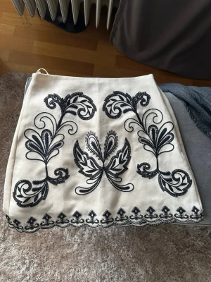 Vit kjol med svart broderi - krämvit kjol med svarta detaljer, från ginatricot i storlek 34. Helt slutsåld och oanvänd