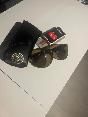 Ray-Ban - Klassiska svarta Wayfarer solglasögon från Ray-Ban med bruna linser. Säljes med originalfodral, putsduk och tillbehör. Snygg och tidlös modell som passar till det mesta. Perfekt accessoar för soliga dagar. Köpte på Synsam. Kan skicka fler bilder 