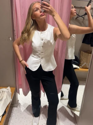 Vit figursydd väst med knappar - Snygg vit väst i figursydd modell med rund halsringning och silverfärgade knappar framtill. Västen är oanvänd och har prislappen kvar fortfarande så som ny😊