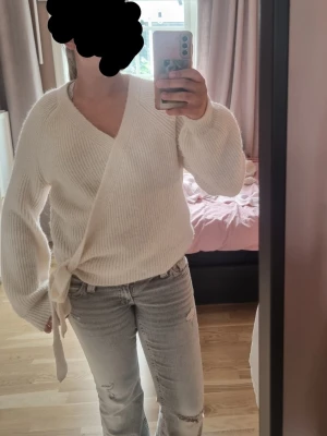 Vit omlottstickad tröja med knytband - Mysig vit stickad omlott-tröja med knytband i sidan och ribbad struktur. Den är ljusbeige. Den är I strl M men passar för folk med L skulle jag säga. Från only. Den är lite för stora för mig så bilden blev inte superbra. Kom gärna med prisförslag! 