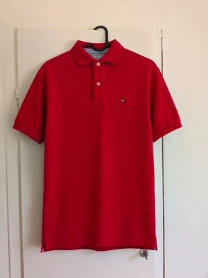 Tommy Hilfiger piké - Klassisk röd pikétröja från Tommy Hilfiger med broderad logga på bröstet. Stilren modell med krage och knappdetaljer, passar perfekt till jeans, chinos eller shorts. ❤️ 👕 Storlek: M ✨ Skick: Bra, men den har några skador! 📦 Skickas snabbt 💌 Skriv vid frågor eller om du vill ha mått!