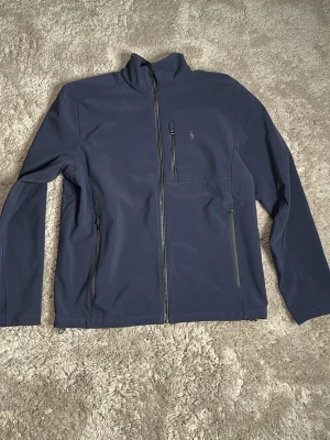 Mörkblå Ralph lauren jacka - Snygg Ralph lauren vindjacka som är mjuk o skön. Skick 9/10 använd fåtal gånger. Nypris ligger runt 3000. Kan tänka mig att gå ner i pris vid smidig förhandling. Skriv vid frågor o funderingar.