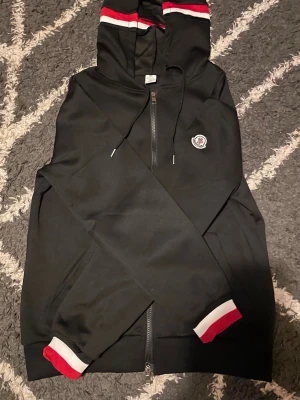 Svart Moncler zip up hoodie - Snygg svart hoodie från Moncler. Helt ny och pris kan diskuteras därför tar jag gärna emot prisförslag 
