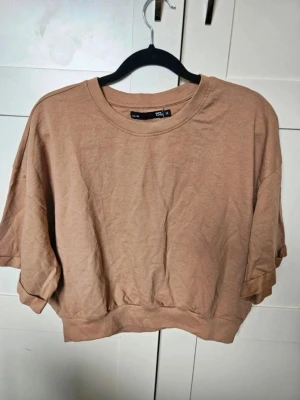 Beige croppad t-shirt från 157 - croppad tröja från 157  Säljer en croppad tröja från 157 i storlek M. Tröjan har korta ärmar, rund hals och bred ribbad kant nedtill. Tillverkad i mjuk bomull, perfekt för chill dagar. Enkel och stilren design som är lätt att matcha med jeans eller shorts.  Kan även hämtas I Partille  E1