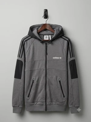 Grå hoodie med svarta detaljer från Adidas - Snygg grå hoodie från Adidas med svarta detaljer på ärmar och huva. Klassiska tre ränder längs axlarna och dragkedja framtill. Adidas-logga på bröstet och ryggen. Två fickor med dragkedja och ribbade muddar. Perfekt för en sportig och avslappnad stil.