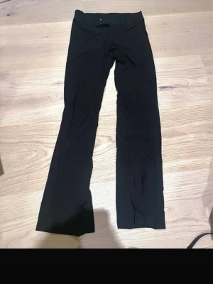 Svarta lågmidjade kostymbyxor - Säljer ett par svarta lågmidjade kostymbyxor. De är stretchiga och sitter tajt upptill men har utsvängda ben. Perfekta till en avslappnad och trendig look. Materialet känns mjukt och följsamt.
