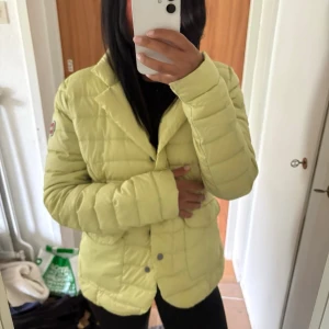 Ljusgul dunjacka från Colmar - Snygg ljusgul dunjacka från Colmar med quiltad design och rundad krage. Jackan har tryckknappar framtill och en patch med Colmar-loggan på ärmen. Perfekt för kalla vinterdagar och ger en fräsch look till din outfit.