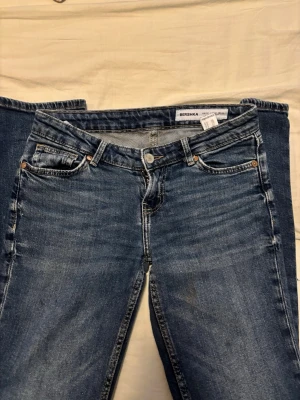 Blå jeans från Bershka - Säljer blåa låg midjade jeans från bershka.                    Har använd ganska mycket men dem har inga fläckar, förutom 2 små hår vid bakfickorna, se på 2 sista bilderna. Jag säljer för dem inte passar mig längre.                           Skriv gärna om ni har några frågor💕