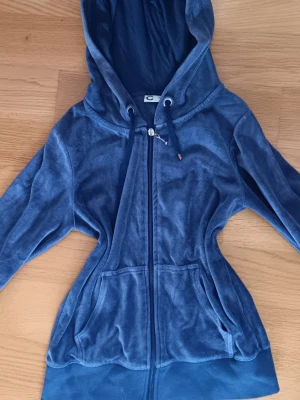 Blå y2k hoodie - Mysig blå hoodie i mjuk velour med dragkedja framtill och två stora fickor. Tröjan har huva med dragsko och ribbade muddar vid ärmslut och nederkant. Ger av en vintage y2k vibe. Säljer en i rosa också, båda för 100 kr. Pris kan diskuteras 💕