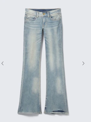Ljusblå bootcut jeans - Säljer ett par ljusblå bootcut jeans med utsvängda ben och klassisk femficksdesign. Jeansen har en snygg tvätt med slitningar framtill och stängs med knapp och dragkedja. Perfekta för en avslappnad och trendig look.
