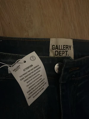 Gallery Dept. jeans med patchwork - Helt nya, oanvända Unika  mörkblå jeans från Gallery Dept. med cool patchwork-design på ena benet. Jeansen har flera grova, ljusa applikationer som ger en riktigt edgy och trendig look. Klassisk femficksmodell i denim med knappgylf.