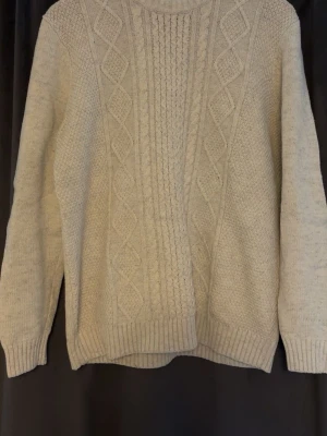 Beige stickad tröja Hampton Republic - Klassisk beige stickad tröja från Hampton Republic med snyggt flätmönster framtill. Tröjan har rund halsringning, ribbade muddar och är tillverkad i ett mjukt material som passar perfekt för kyligare dagar.