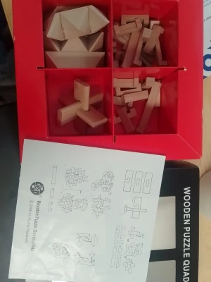 Träpussel Wooden Puzzle Quadruplets - Säljer ett set med fyra olika träpussel i naturfärgat trä. Pusslen kommer i en röd låda och inkluderar instruktioner med ritningar för montering. Perfekt för dig som gillar kluriga utmaningar och hjärngympa.