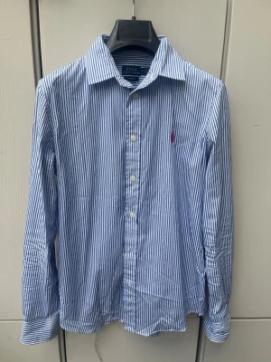 Ralph Lauren Skjorta  - Snygg blå randig Ralph Lauren skjorta i storlek S/Xs. Bra skick inga defekter eller liknande. Kom privat för fler frågor✅