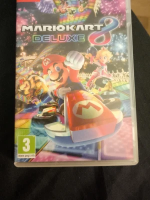 Mario Kart 8 Deluxe Nintendo Switch - Mario Kart 8 Deluxe till Nintendo Switch med färgstark omslagsdesign. Spelet har ikoniska karaktärer som Mario och Peach i sina gokarts på en neonfärgad bana. Perfekt för dig som gillar fartfyllda racingspel och multiplayer.