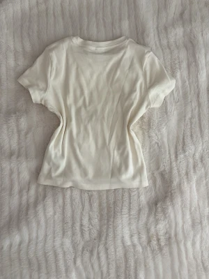 Vit ribbad t-shirt från Lindex - Säljer en enkel och stilren vit ribbad t-shirt från Lindex. T-shirten har korta ärmar och rund halsringning. Perfekt basplagg som passar till allt och är gjord i mjuk bomull för skön känsla hela dagen. ❤️🫰🏻
