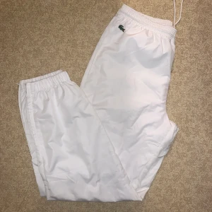 Vita Lacoste trackpants - Assnygga Lacoste trackpants i storlek M, med dragsko. Knappt använda, något för små för mig.  Köpare står för frakt 