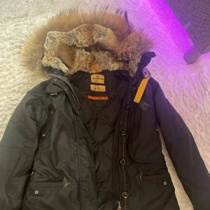 Parajumper Doris jacka  - Säljer min fina Parajumper Doris jacka i färgen svart. Jackan är i storlek S passar som M också. Har 4 fram fickor, knäppning med dragkedja. Äkta päls i luvan och kragen. Jackan är i fint skick. Köpt för 9 999:- pris kan diskuteras Skriv gärna vid intress