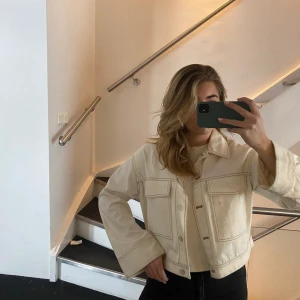 Vårjacka med vida ärmar - Superfin benvit vårjacka med beigea kontrastsömmar. Passar utmärkt till våren över en klänning eller till jeans. Denimliknande material. 