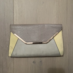 BEIGE/GUL KUVERTVÄSKA 💛 - Säljer den här fina kuvertväskan i beige/gul med kedja ifrån New Look. Nyskick! 💕 