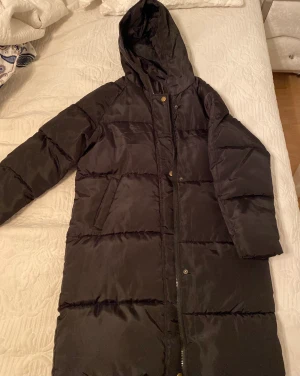 Svart puffer jacket - Lång Svart dunjacka i storlek S, helt ny aldrig använd eftersom det var fel storlek. 