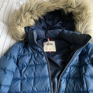 Tommy Hilfiger Vinterjacka  - Säljer min vinterjacka då jag tröttnat på den. Fint skick. Luvan kan man ta av. Pälsen på luvan kan man välja att ta av. Finns fler bilder. 