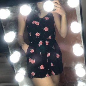 Svart playsuit med blommor - Playsuit med blommor på från hm. Den har 2 fickor på höfterna. Använd få gånger så skicket är som nytt. Säljer den för 60kr plus frakt😊💕