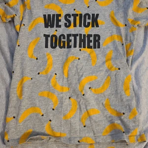 Den kommer från Ica maxi. - Det är en pyjamas tröja med bananer på. Det står we stick toaletter på engelska med svart text.