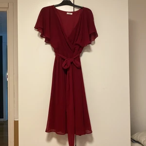 Klänning Goddiva - Mörkröd midiklänning i 100% polyster med knytning i midjan i storlek 42. Aldrig använd. Ordinarie pris 699kr på Bubbleroom.