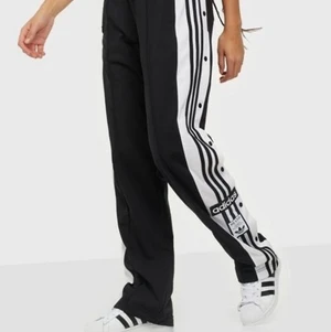 Adidas byxor med knappar - Ett par adidas byxor med knappar på sidan i ett väldigt bra skick!!
