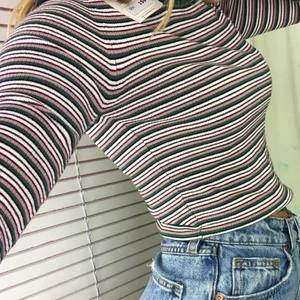 Långärmad randig tröja - Randig långärmad från Pull&Bear. Grön, rosa och vit, lite inslag av vinröd/svart. Bra skick! Inget slitage. Stl M men sitter tight på mig som brukar ha S. 