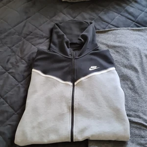 Gråsvart nike tech fleece - Tjena, säljer nu min tech fleece då jag har bytt stil. Hoodien är I bra skick, är lite noppig på baksidan av luvan men det syns inte när man används den. Den har inga fläckar och materialet är jätte mjukt och skönt. Den är L men passar också M. För fler bilder eller om ni har några frågor, kom privat.  OBS. Det som ser ut som hål på luvan är bara noppar och kommer att tas bort vid köp.