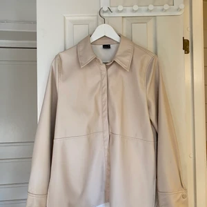 Beige skjorta i skinnimitation  - Skjorta från Gina. Fin i kvaliten och använd fåtal gånger. Storlek 36 