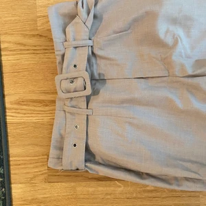 Kostymbyxor - Grå/beiga kostymbyxor från nakd med skärp i midjan. Knappt använda, lite kortare i byxlängden. 