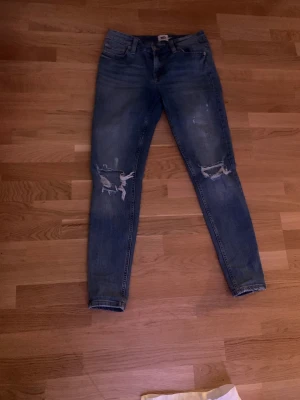 Ett par jeans. - De har hål på knäna. De är tvättade. 