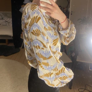 Blus från Rodebjer - En så fin och elegant blus från Rodebjer. Har lite vidare ärmar med resår längst ut samt en båtformad skärning i halsen. Mönster i form av tranor och vingar i gult och blått. Absolut finaste plagget att ha på sommaren🍇 Står ingen storlek men passar XS/S. 