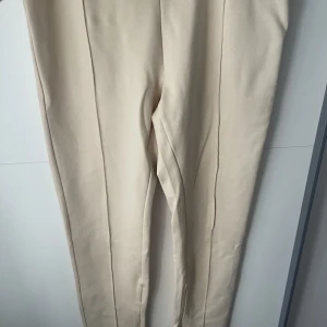 Beigea kostymbyxor - Säljer ett par beigea kostymbyxor från Ullared. Använda 1 gång, har resår i midjan. Sitter väldigt fin på. Strl 44-46. Stryker innan frakt!❤️