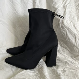 Svarta boots  - Svarta höga boots med spännband runt ankeln. Endast testade. Klackhöjd: 11 cm. 