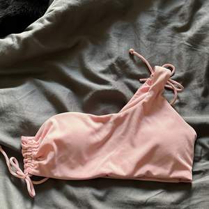Helt oanvänd bikini topp som är one shoulder i en ljusare rosa färg. Jättefin men kommer inte få användning av den - Storlek M