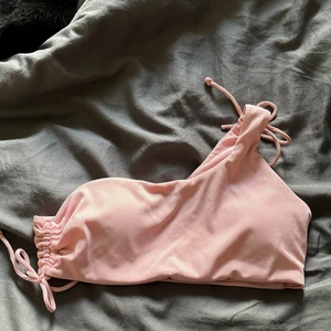 Bikini Topp - Helt oanvänd bikini topp som är one shoulder i en ljusare rosa färg. Jättefin men kommer inte få användning av den - Storlek M
