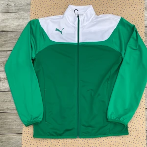 Puma Tracksuit Jacket Grön L - Puma trackjacka i vit och grönt i tre (!) olika nyanser. Är storlek large men passar även de som har medium (oversized). 9/10 condition. Passar till svart, gult, rött (i mörkare nyanser), blått (inte så mörka nyanser) och säkert annat du har i garderoben🙌🏻