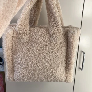 Handväska i teddy - En mellanstor handväska i teddy. Aldrig använd. Säljer pga flytt