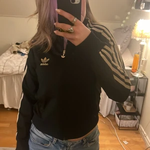 Adidas zip tröja - Säljer min adidas zip hoodie för kommer inte till andvändning🫶🏼så den är i bra sick, den är svart med guldiga sträck💕